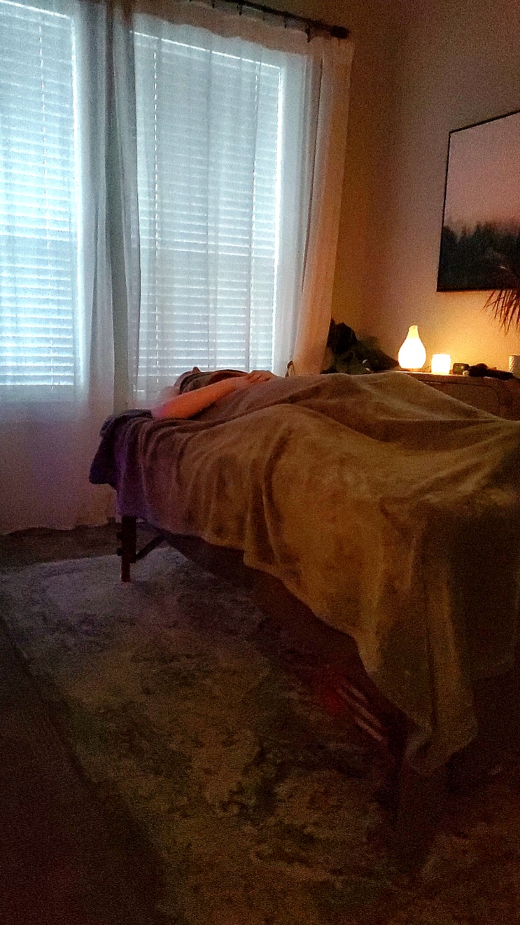A client resting under a warm blanket during a session at Quiet Light